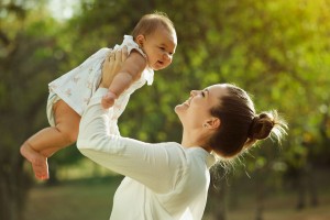 woman holding baby up outside