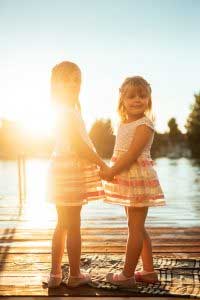 two young girls on dock at lake at sunset