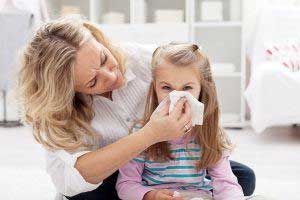 mother helping young girl blow nose