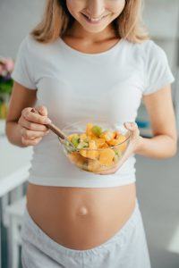 pregnant woman eating a bowl of fruit