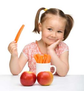 young girl with pigtails holding carrot