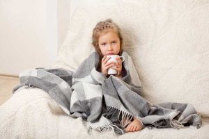 young girl wrapped in blanket with coffee mug