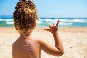little girl at beach showing surf shaka sign